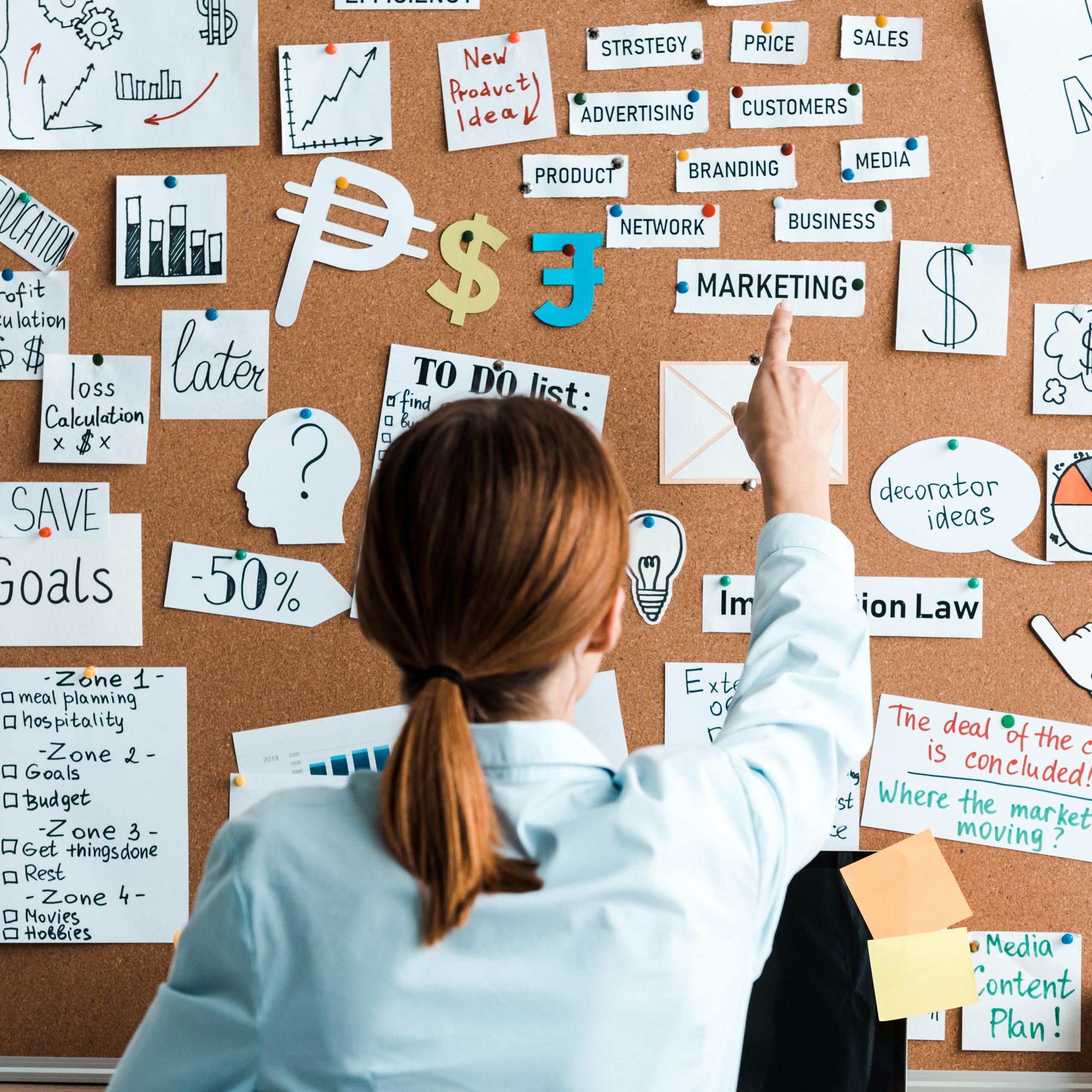 cropped view of businesswoman pointing with finger at marketing lettering on notice board