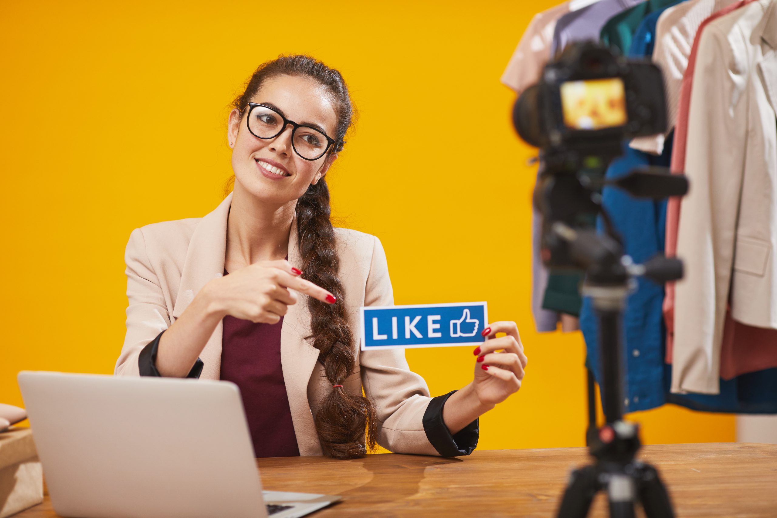 Portrait of contemporary young woman holding LIKE word and smiling at camera while filming video for beauty and lifestyle channel, copy space